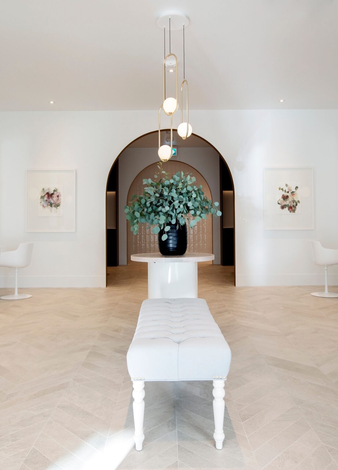 Entrance view of Wish Dry Bar showing arched doorway, white tufted bench, and elegant floral arrangement